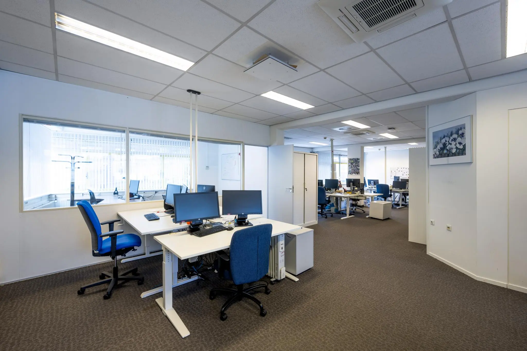 Modern ingericht kantoor aan de Jan Tooropstraat met werkplekken, bureaustoelen en computers.